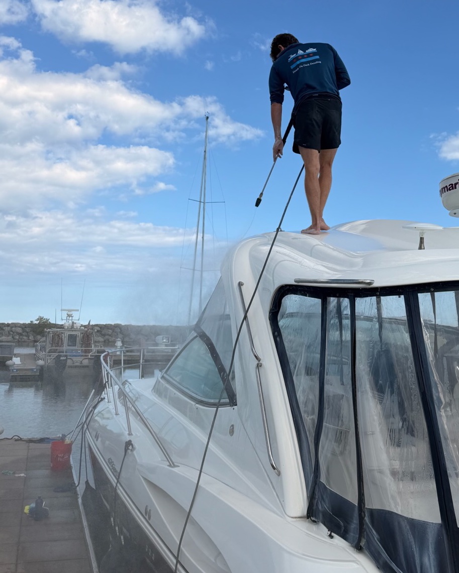 Crew member washing down the exterior of a boat