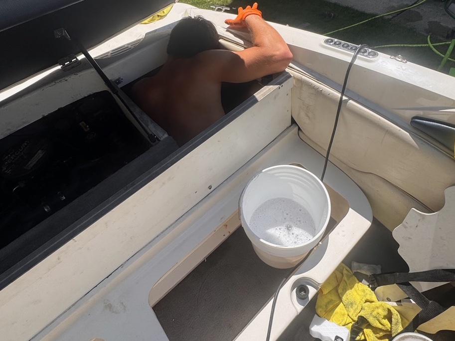 Crew member cleaning inside a boat's interior storage compartment