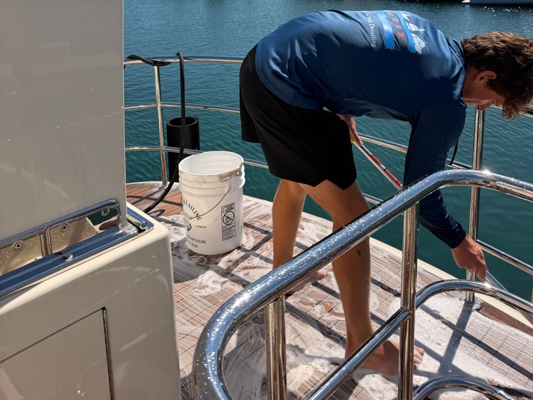 Crew member scrubbing a boat's teak swim platform